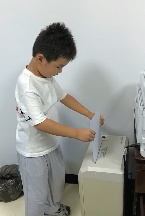 宸宸帮哥哥将废纸用碎纸机打碎